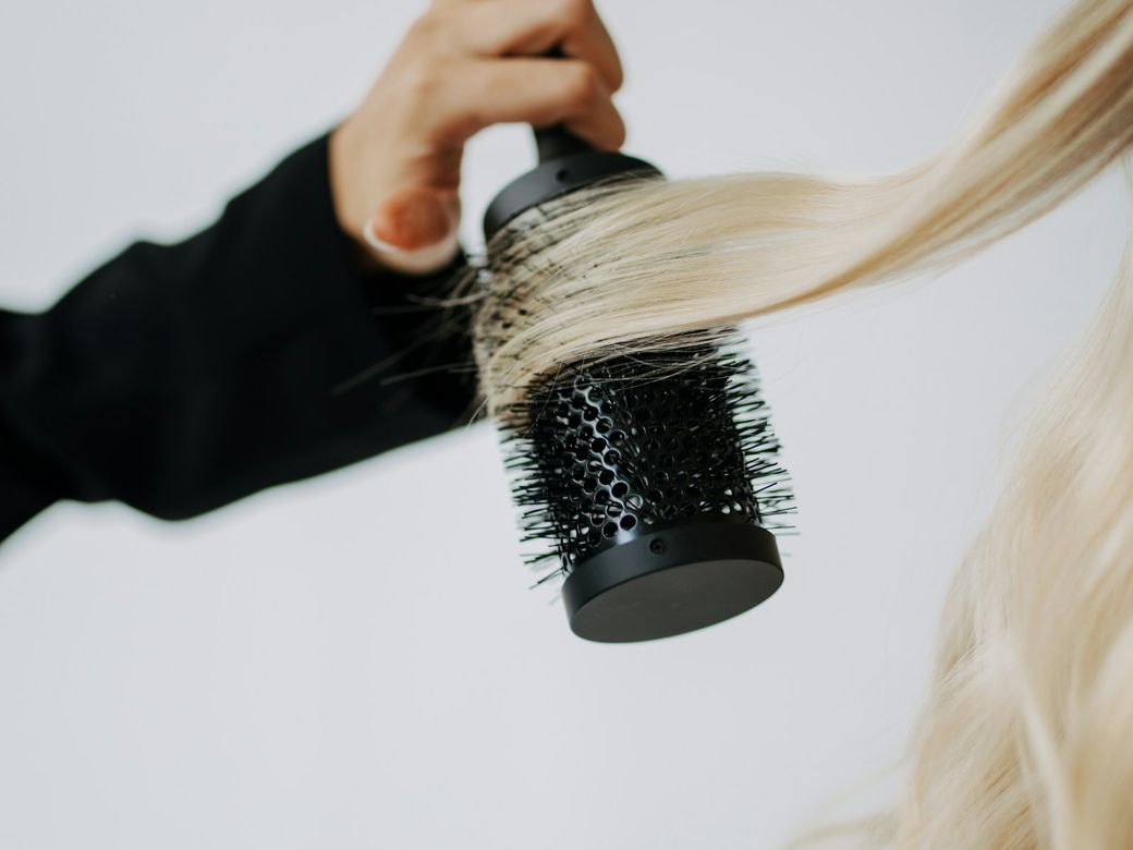 Long blonde hair being blow-dried with a round brush